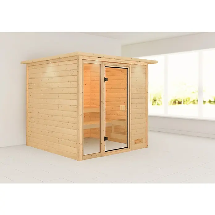 Karibu Massivholzsauna Jutta - L x B x H: 210 x 224 x 191 cm, Ohne Ofen, Mit Dachkranz und Beleuchtung - Eine moderne Holzsauna mit Glastür, die in einem hellen Raum mit Fliesenboden steht. Entspannungs- und Wellnessbereich.