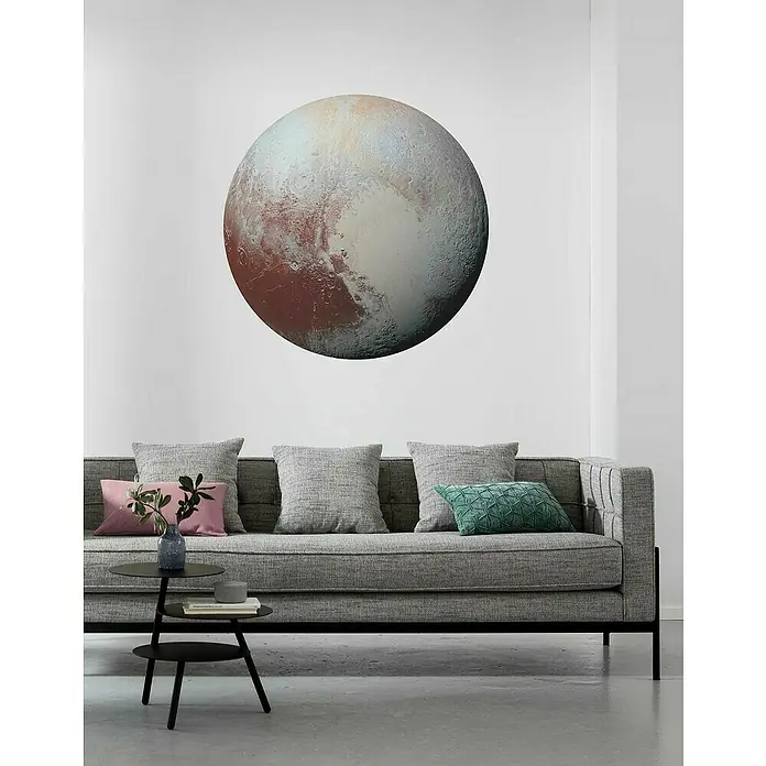 Komar Dots Fototapete rund Pluto - 125 cm, Selbstklebend - Wohnzimmerdekor mit einem grauen Sofa, Kissen und einem runden Pluto-Wandbild, das dem Raum eine kosmische Note verleiht.
