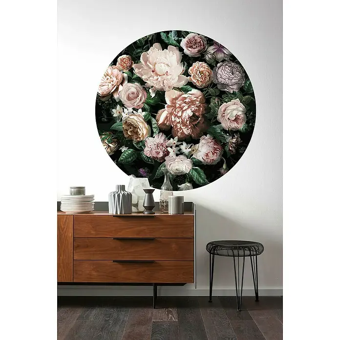 Komar Dots Fototapete rund Flower Couture - 125 cm, Selbstklebend - Wanddekoration mit floralem Muster über einer Holzkommode mit stilvoller Anordnung von Dekorationsgegenständen und einem eleganten Hocker.