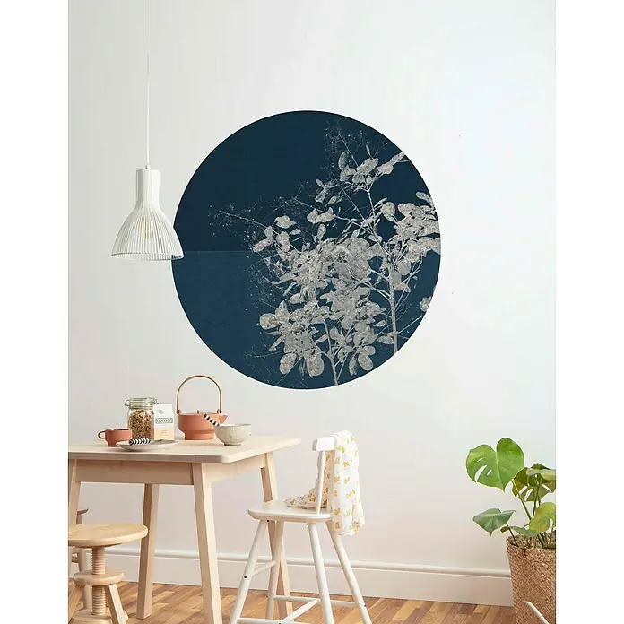 Komar Dots Fototapete rund Branch - 125 cm, Selbstklebend - Ein Wandbild mit einem dunkelblauen Kreis, der mit silbernen Blättern verziert ist, hängt über einem Holztisch mit Teegeschirr.