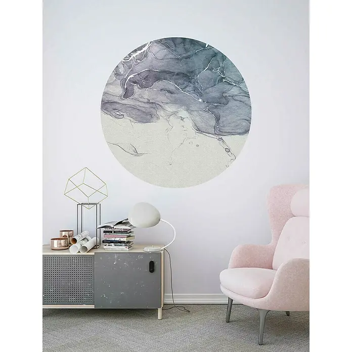 Komar Dots Fototapete rund Fabled INK - 125 cm, Selbstklebend - Ein stilvolles Interieur mit einem hellrosa Sessel und einem Schrank, an dem ein modernes Kunstwerk an der Wand hängt.