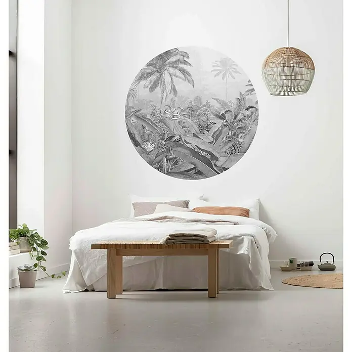 Komar Dots Fototapete rund Amazonian Spirit - 125 cm, Selbstklebend - Schlafzimmer mit einem weißen Bett, einer Bank aus hellem Holz und einer runden Dschungel-Wanddeko, die dem Raum eine tropische Atmosphäre verleiht.