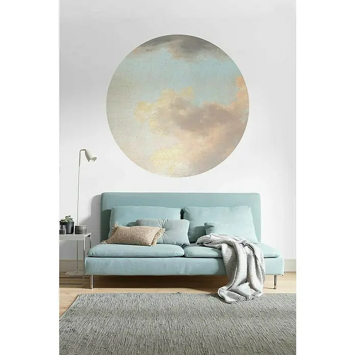 Komar Dots Fototapete rund Relic Clouds - 125 cm, Selbstklebend - Ein Wohnzimmer mit einem hellblauen Sofa, einem grauen Teppich und einem kreisförmigen Wolkenbild an der Wand für eine ruhige Atmosphäre.