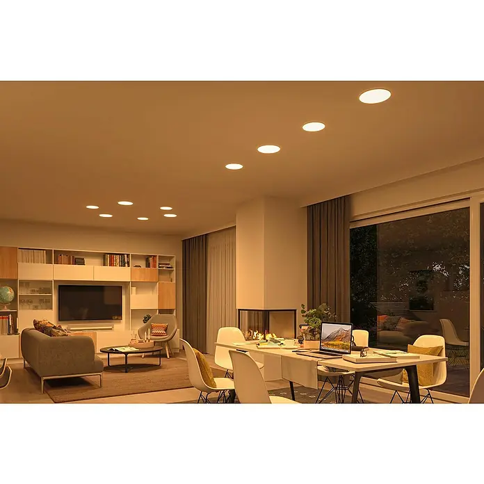 Paulmann LED-Panel rund Veluna VariFit - 17 W, Ø x H: 18,5 x 3,1 cm, Satin, Warmweiß, Nicht Dimmbar - Deckenleuchten erhellen ein stilvolles Wohnzimmer mit Esstisch, Bücherregal und Kamin, wodurch eine warme und einladende Atmosphäre entsteht.