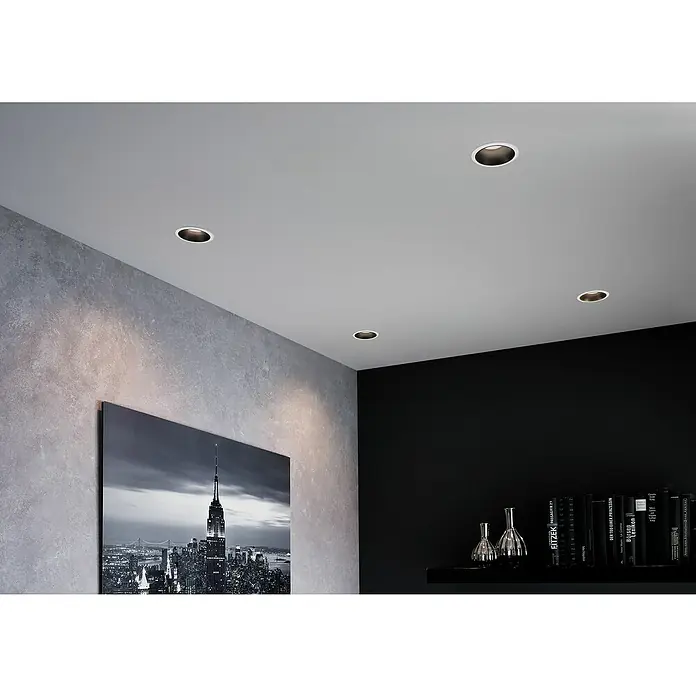 Paulmann LED-Einbauleuchte Cole - 6,5 W, Weiß/Schwarz, Warmweiß, 1 Stk. - Deckeneinbaustrahler mit runden Gehäusen in einer Ecke eines modernen Raumes. Die Deckenleuchten beleuchten die Wand und das Zimmer darunter.