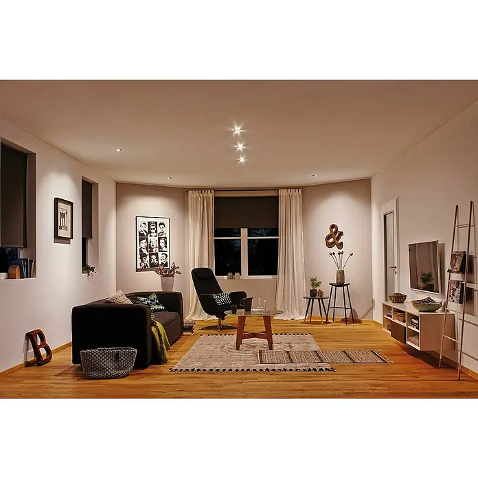 Paulmann LED-Einbauleuchten-Set rund6 W, Chrom matt, 3 Stk., Warmweiß - Wohnzimmer mit dunklem Sofa, Sessel und Teppich auf Holzboden. Helle Wände, Fenster mit Rollos und moderne Deckenspots sorgen für Gemütlichkeit.