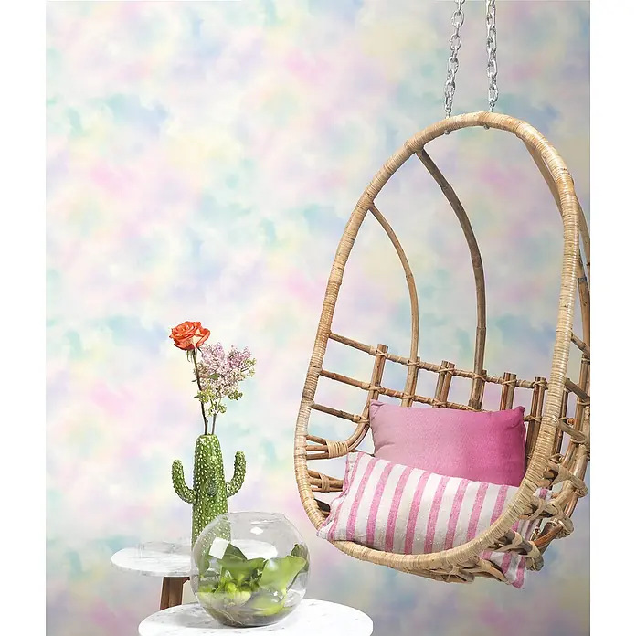 Rasch Kids & Teens III Vliestapete Weltall - Bunt, Grafisch, 10,05 x 0,53 m - Hängesessel aus Rattan mit rosa Kissen und einem dekorativen Tisch mit Vase und Kakteenskulptur.