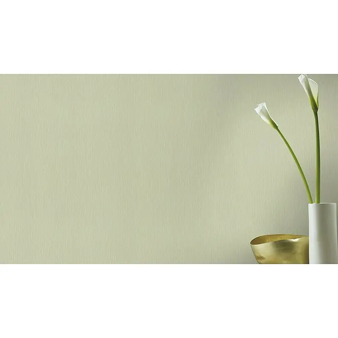 Rasch BARBARA Home Collection II Vliestapete - Pastellgrün, Uni, 10,05 x 0,53 m - Nahaufnahme von Callas in einer weißen Vase, die auf einem Tisch mit einer goldenen Schale stehen, vor einem hellgrünen Hintergrund.