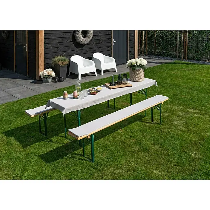 Bierbankauflagen-Set - Grau, 240 x 70 cm, 100 % Polyester, 3 -tlg. - Ein Gartentisch mit Bänken auf einem Rasen. Die Tischdecke und Sitzkissen sind hellgrau. Zwei weisse Stühle und Blumendeko sind auch sichtbar.