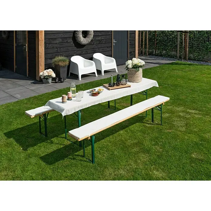 Bierbankauflagen-Set - Creme, 240 x 70 cm, 100 % Polyester, 3 -tlg. - Ein Gartentisch mit Bänken und weißen Polstern steht auf einer grünen Rasenfläche, bereit für eine Mahlzeit im Freien.