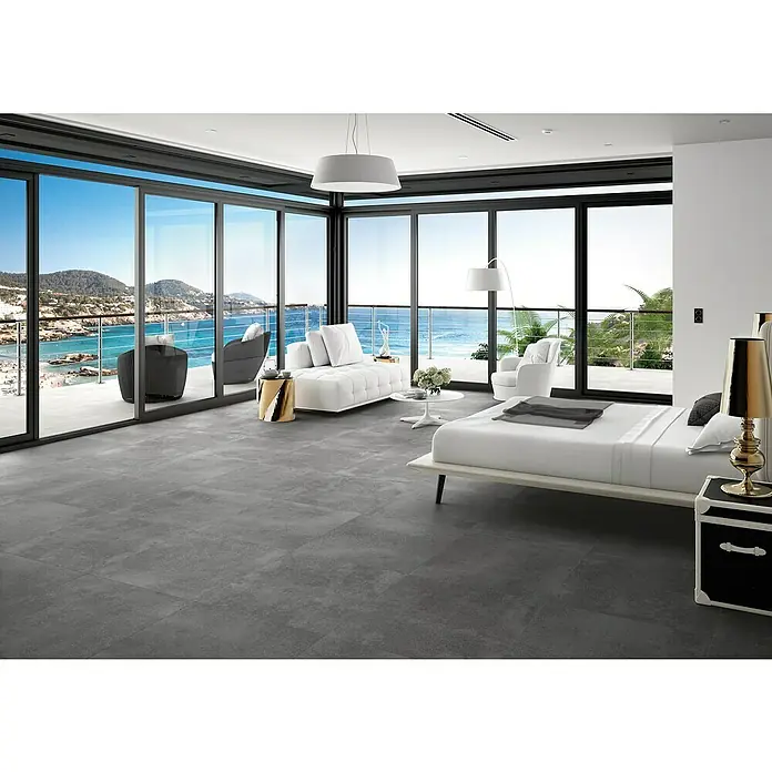 BHS Showroom Pavimento porcelánico Claire - 60 x 60 cm, Cemento, Rectificado - Dormitorio luminoso con baldosas grises y vistas al océano a través de grandes ventanas. Decoración moderna y mucha luz natural.