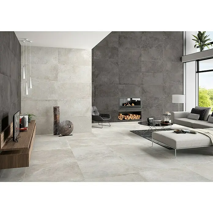 BHS Showroom Pavimento porcelánico Lorraine - 120 x 60 cm, Gris, Rectificado - Salón luminoso y moderno con baldosas de gran formato en gris claro y pared decorativa en gris oscuro con chimenea.