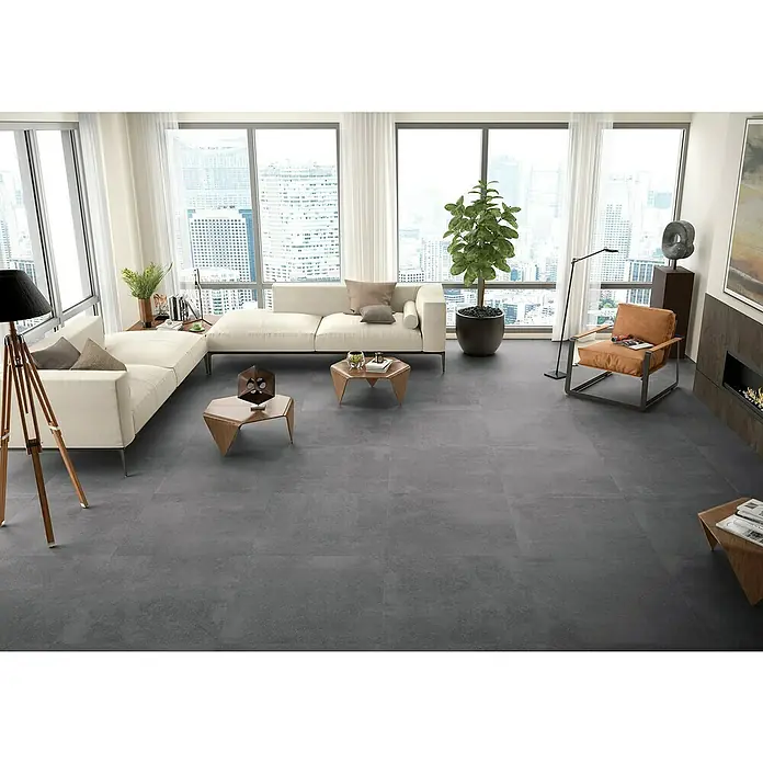 BHS Showroom Pavimento porcelánico Claire - 100 x 100 cm, Cemento, Rectificado - Un salón moderno con baldosas grises, un sofá blanco y grandes ventanales con vistas a la ciudad.