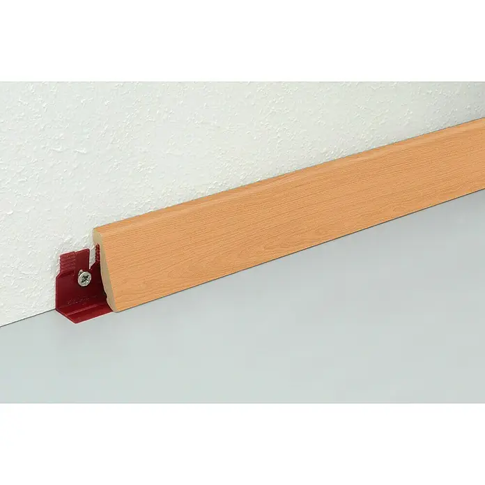 Profiles and more Sockelleiste FU147H Buche Exquisit - 240 cm x 18,5 mm x 38,5 mm, MDF - Nahaufnahme einer hellbraunen Sockelleiste mit roter Halterung an einer weißen Wand, die einen sauberen Übergang zum Boden bildet.