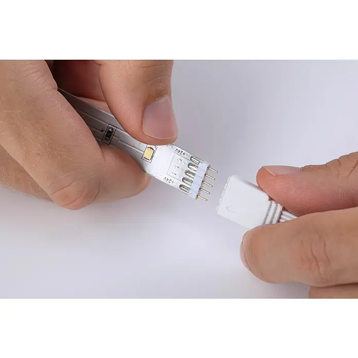 Paulmann MaxLED 250 Tira LED - Largo: 3 m, Color de luz: RGBW, 20 W, 690 lm - Un primer plano de manos conectando una tira de luz LED a un conector. La tira de luz es blanca y el conector es blanco.