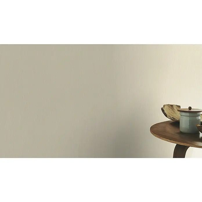 Rasch BARBARA Home Collection II Vliestapete - Beige, Uni, 10,05 x 0,53 m - Nahaufnahme eines runden Holztisches mit einer hellblauen Keramikdose mit Holzdeckel und einer Holzschale, die eine warme, minimalistische Ästhetik ausstrahlt.