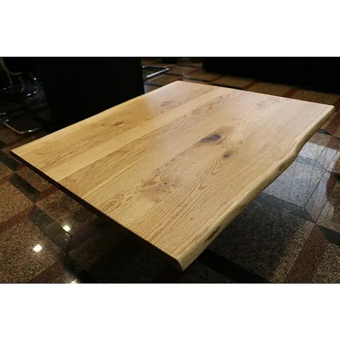 Exclusivholz Tablero de mesa - Roble, 80 x 80 x 2,6 cm - Primer plano de una mesa de madera clara con borde natural y grano de madera visible, sobre un suelo de baldosas estampado.