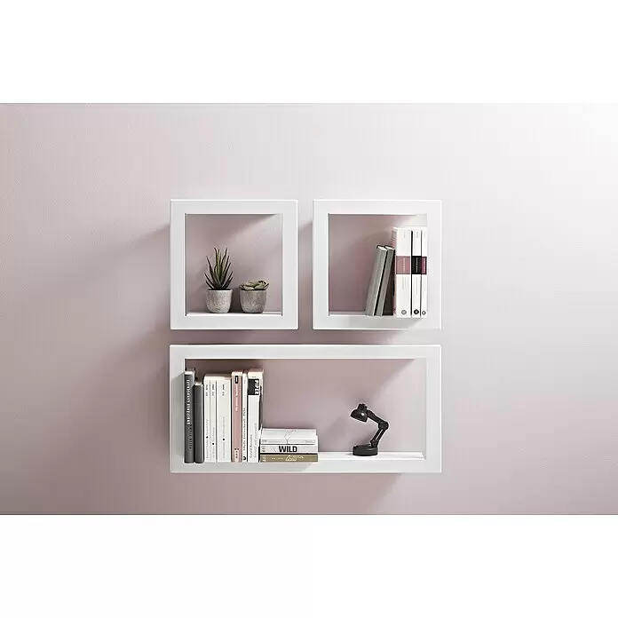 Dolle Estante flotante Figura - 285 x 285 x 85 mm, Blanco, Carga soportada: 15 kg - Tres estanterías blancas de pared en una pared rosa, con libros, plantas y una pequeña lámpara.