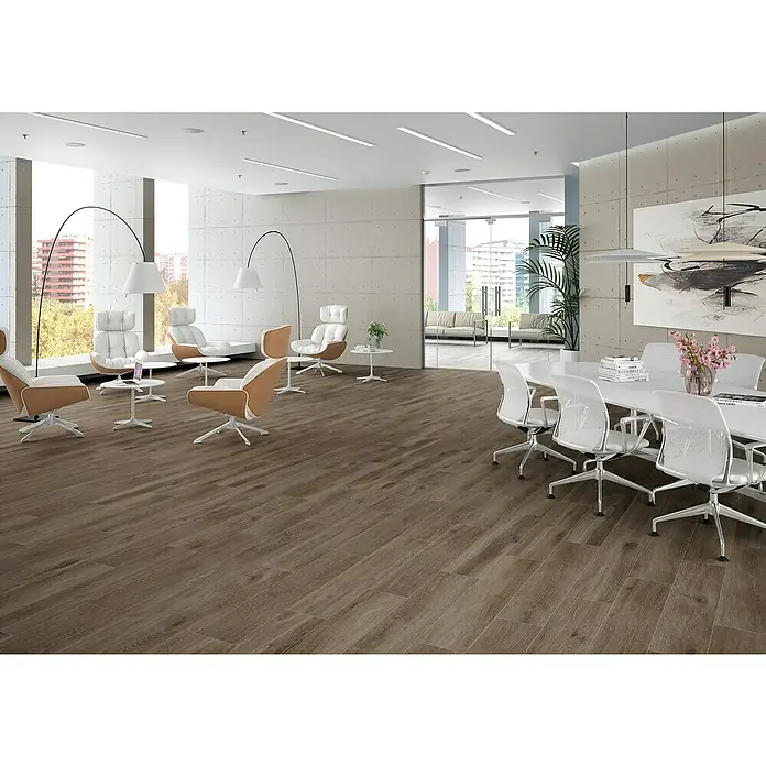 BHS Showroom Pavimento porcelánico Sanford Soft - 120 x 23 cm, Marrón, Rectificado - Acogedor espacio de oficina con suelo de madera, muebles de diseño y mesa de reuniones bajo iluminación moderna. Ambiente elegante para trabajar.