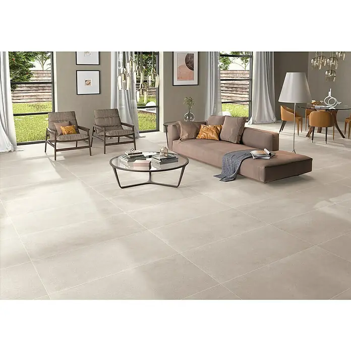 BHS Showroom Pavimento porcelánico Claire - 120 x 60 cm, Arena, Rectificado - Salón luminoso con baldosas beige, sofá, sillones y mesa de centro. Las baldosas son la característica principal, dando un toque moderno.