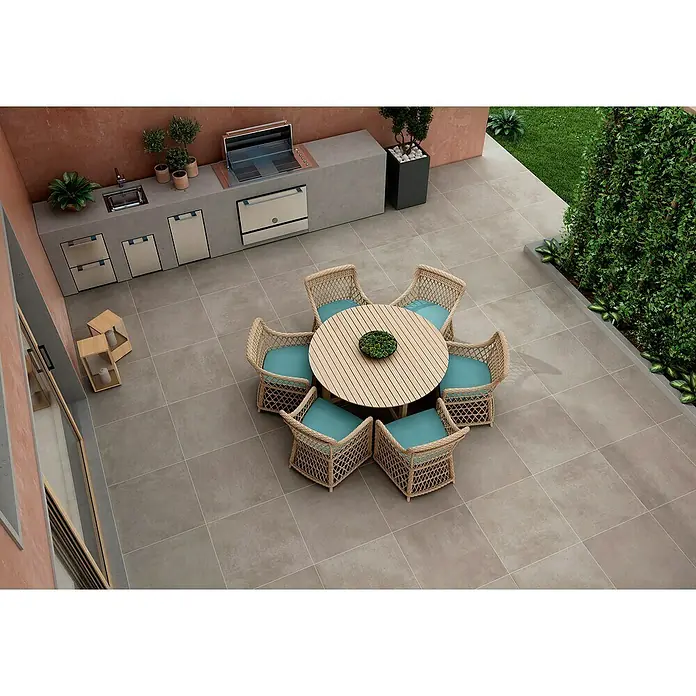BHS Showroom Pavimento porcelánico Rodano - 60 x 60 cm, Taupe, Rectificado - Acogedora escena de jardín con mesa redonda de madera y seis sillas de ratán con cojines turquesa, ideal para la relajación al aire libre.