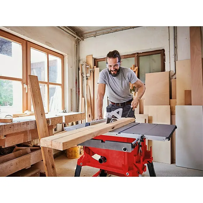 Einhell Tischkreissäge TC-TS 2225 U - 2.200 W, Durchmesser Sägeblatt: 254 mm, Schnitttiefe bei 90 °: 80 mm - Ein Mann benutzt eine Einhell Tischkreissäge, um Holz zu schneiden, mit Schutzbrille für die Sicherheit in einer Werkstatt.