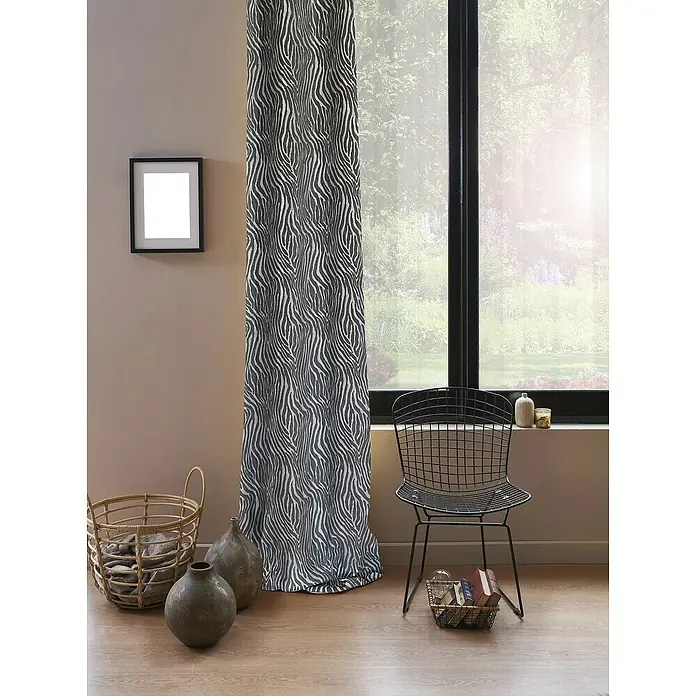Cortina con ollaos Odín cebra - An x Al: 140 x 270 cm, Gris - Imagen de un interior con una cortina estampada, una silla y elementos decorativos. La cortina es llamativa.