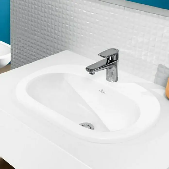 Villeroy & Boch O.novo Einbauwaschbecken - 56 x 40,5 cm, Mit schmutzabweisender Glasur, Hahnloch: Mitte, Ohne Überlauf, Weiß - Nahaufnahme eines modernen, weißen Waschbeckens mit einem eleganten Chromwasserhahn, der das minimalistische Design des Badezimmers unterstreicht.