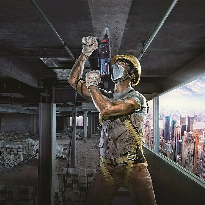 Bosch Professional Kombihammer GBH 240 - 790 W, 2,7 J, SDS-Plus-Aufnahme - Bauarbeiter bohrt mit einer Bosch Bohrmaschine Löcher in eine Betondecke in einem unfertigen Gebäude.
