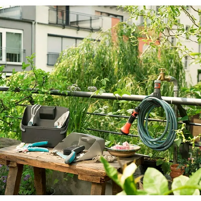 Gardena City Gardening Spiralschlauch - Länge: 7,5 m - Gartengeräte-Set mit praktischer Aufbewahrungsbox und Schlauchaufhängung auf einem Gartentisch im Freien.