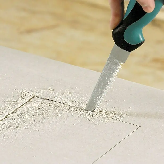 Wolfcraft Gipskartonplatten-Stichsäge - Geeignet für: Gipskartonplatten - Nahaufnahme einer Hand, die mit einer Stichsäge ein Loch in eine Gipskartonplatte sägt. Das Werkzeug erleichtert präzise Ausschnitte.