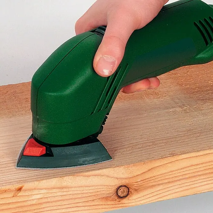 Delta-Haftschleifscheiben - Körnung: 60 - 120, 15 -tlg. - Schleifmaschine bei der Arbeit an einem Holzbrett, ideal zum Glätten und Vorbereiten von Oberflächen für die Weiterverarbeitung.