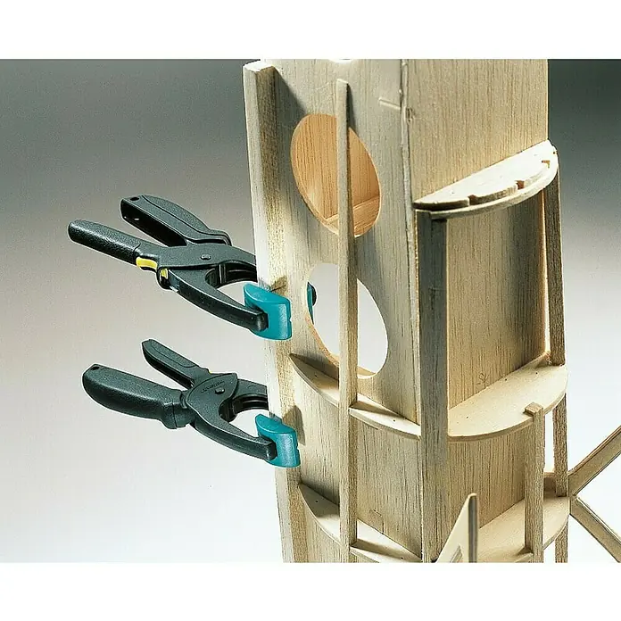 Wolfcraft Pinzas de sujeción Quickfix S - Anchura de sujeción: 30 mm, 2 ud. - La imagen muestra dos pinzas de resorte asegurando una estructura de madera. Estas herramientas son ideales para modelismo y carpintería.