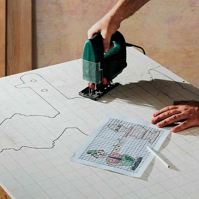 Wolfcraft Juego de hojas de sierra de calar - 12 pzs., Acero HS - Primer plano de una sierra de calar verde en acción, recortando una forma dibujada en una tabla de madera.