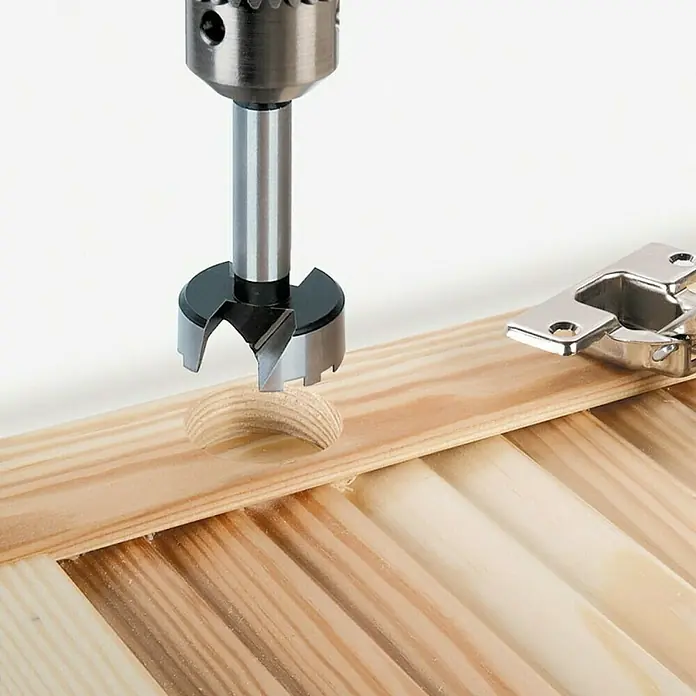 Wolfcraft Set de brocas Forstner - 2 pzs., Diámetro vástago: 10 mm - Broca Forstner perforando un tablero de madera con una bisagra cerca, ideal para embutir bisagras en muebles.