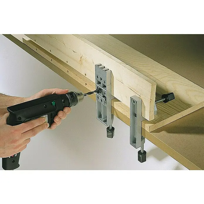 Wolfcraft Plantilla de perforación - Diámetro de la broca: 10 mm - Un taladro eléctrico perfora una abrazadera de madera sujeta a una tabla de madera. Herramienta de carpintería de precisión.