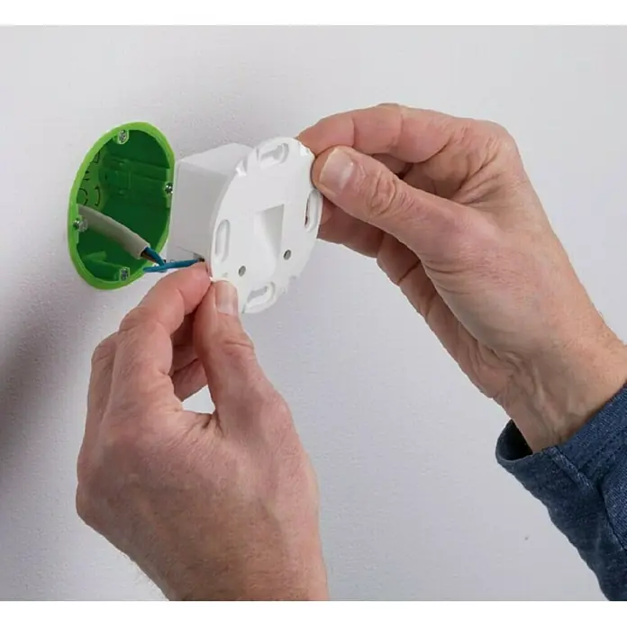 Paulmann LED-Einbauleuchte rund - 2,7 W, Weiß, L x B: 7,8 x 7,8 cm, Rund - Nahaufnahme einer Person, die eine weiße Abdeckung an einer grünen Wandhalterung befestigt, mit sichtbaren Kabeln, die auf eine Elektroinstallation hinweisen.