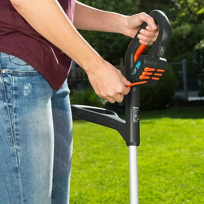 Gardena SmallCut Recortabordes de batería Li-23 R - 14,4 V, 2 Ah, Iones de litio, 1 batería, Ancho de corte cuchilla: 22,3 cm - Una persona utiliza un cortabordes inalámbrico Gardena Li-Ion+, mostrando la facilidad de uso para el mantenimiento del césped.