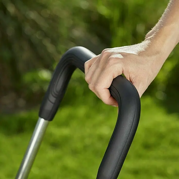 Gardena Carro portamangueras CleverRoll M Easy - Plástico/metal, Capacidad de manguera: 60 m, 13 mm (½'') - Una mano sostiene el mango de una cortadora de césped sobre un fondo verde. Diseño cómodo y ergonómico para fácil manejo.
