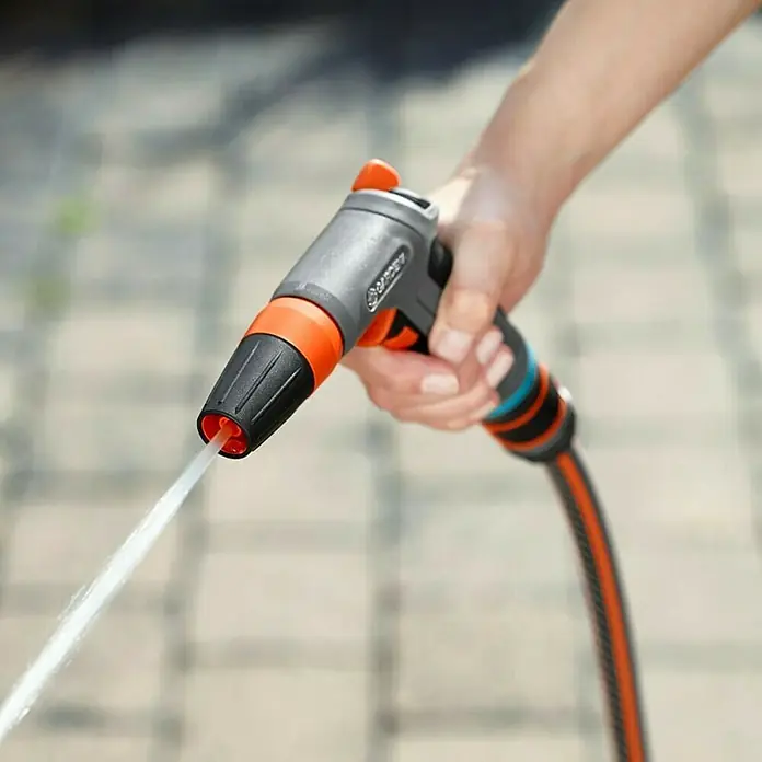 Gardena Comfort Reinigungsspritze - Anzahl Sprühformen: 2 Stk., Kunststoff - Nahaufnahme einer Hand, die eine Gardena-Gartenspritze hält, aus der ein Wasserstrahl kommt.