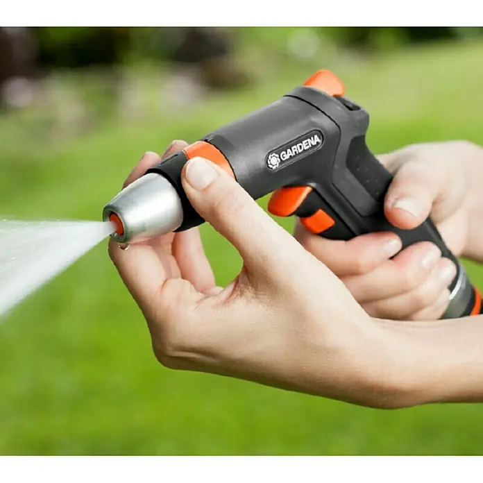 Gardena Premium Reinigungsspritze - Anzahl Sprühformen: 3 Stk., Metall/Kunststoff - Nahaufnahme einer Person, die eine Gardena Gartenspritze benutzt, wobei der Wasserstrahl deutlich sichtbar ist.