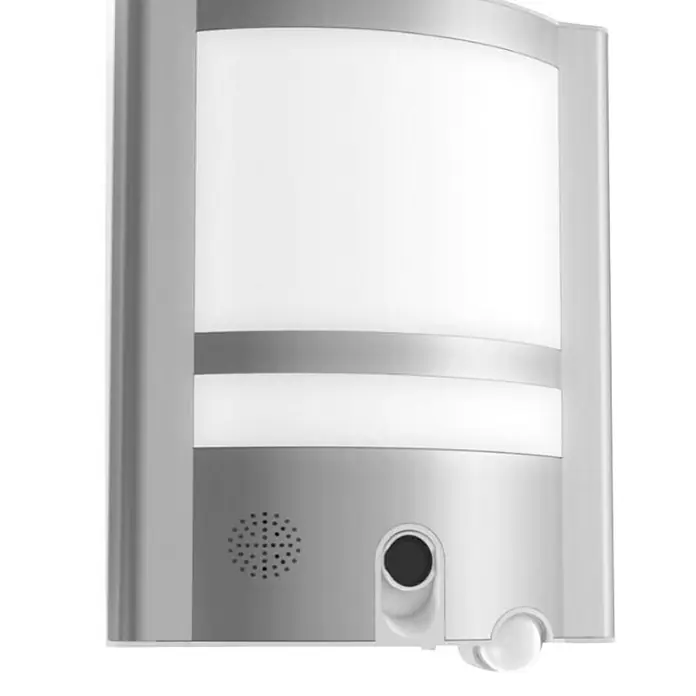 Aplique exterior LED con sensor y cámara HD VESTA - 30 W, L x An x Al: 11 x 26 x 40 cm, Blanco cálido - Imagen de una moderna lámpara de pared LED plateada con detector de movimiento para uso exterior. La luz proporciona seguridad e iluminación.