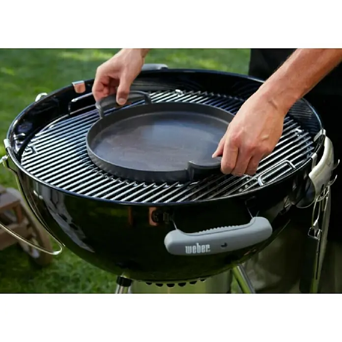 Weber Gourmet BBQ System Grillpfanne - Durchmesser: 38,6 cm, Gusseisen - Hier ist ein Weber Grill mit einer runden Grillplatte, die von Händen platziert wird. Ideal zum Kochen im Freien.