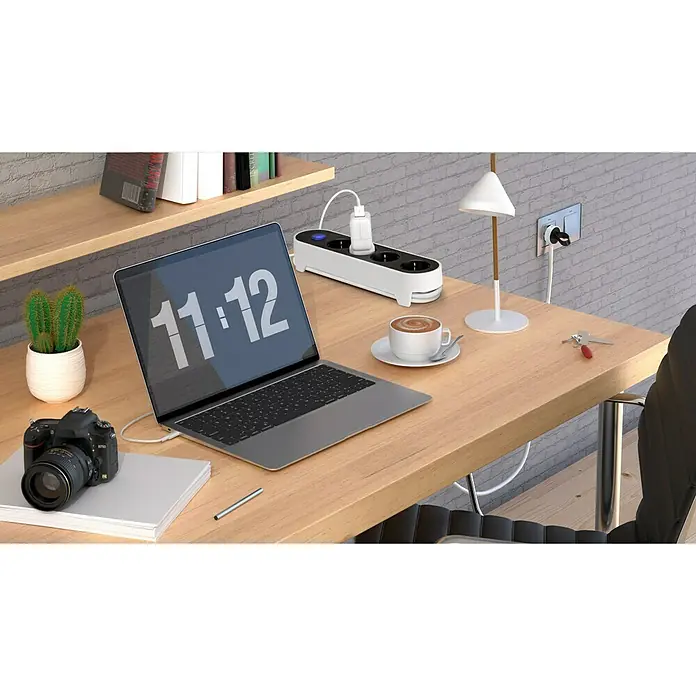 Simon Base de enchufe múltiple - x 4, Negro/blanco, Longitud del cable: 1,4 m, IP20, Con interruptor - Un escritorio moderno con un portátil, café y una regleta blanca que destaca como producto principal.
