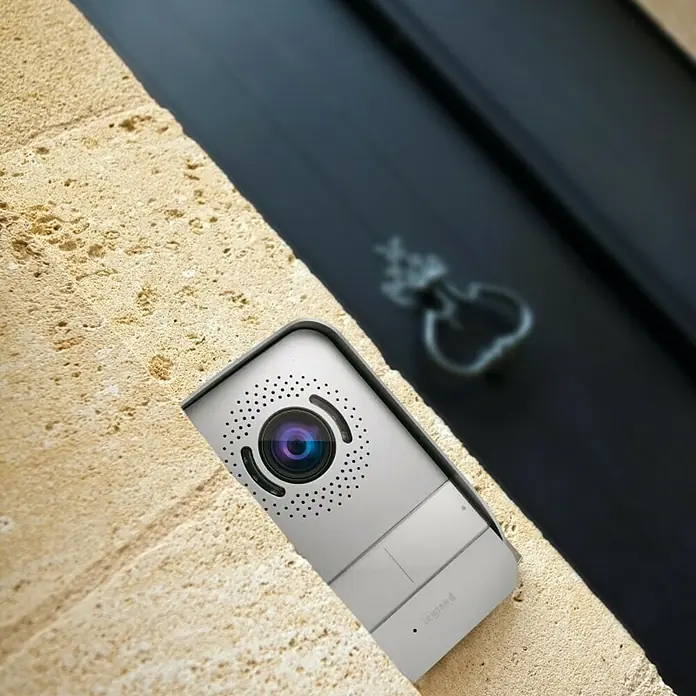 Legrand Videoportero en color Módulo Exterior - Casa unifamiliar - Cámara de seguridad Legrand montada en una pared de piedra junto a una puerta, brindando seguridad y vigilancia.