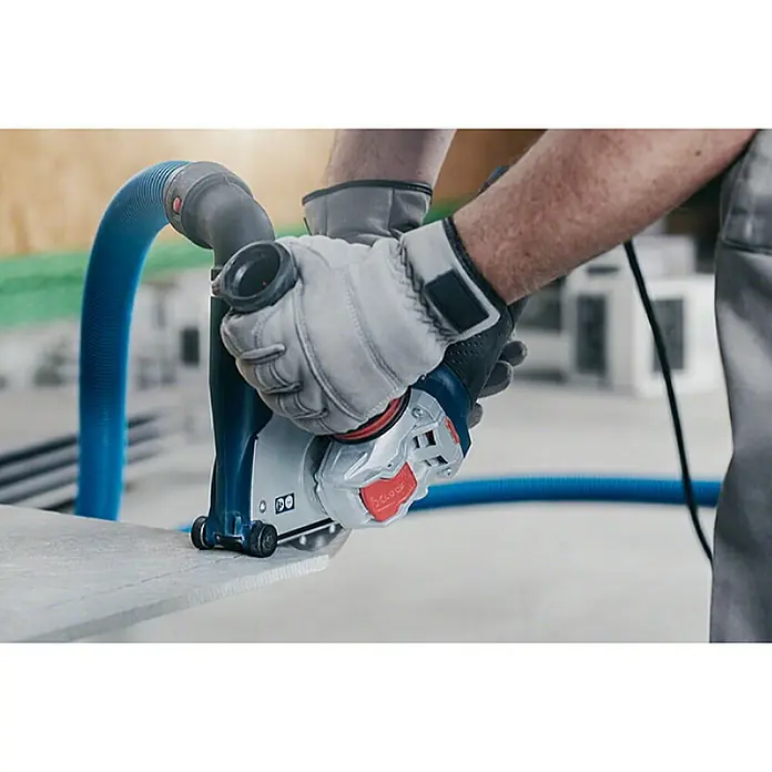 Bosch Professional X-Lock Elektro-Winkelschleifer GWX 9-125 S - 900 W, Durchmesser Scheibe: 125 mm, Leerlaufdrehzahl: 2.800 U/min - 11.000 U/min - Das Bild zeigt eine Mauernutfräse in Aktion, die von einer Person mit Arbeitshandschuhen bedient wird, um präzise Schnitte zu erzeugen.