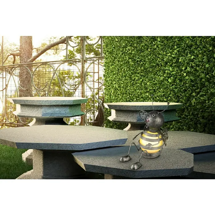 Globo Solar-Dekoleuchte Biene - 0,06 W, L x B x H: 210 x 190 x 240 mm, Schwarz, Gelb, IP44 - Eine dekorative Metallbiene mit gelben Streifen sitzt auf einem grauen Steintisch im Freien, umgeben von Grün.