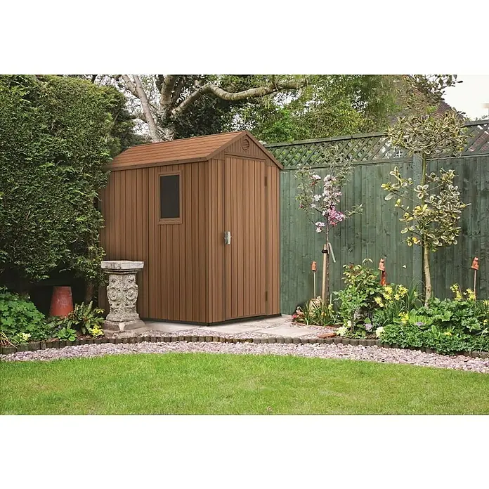 Keter Caseta de jardín Darwin 4x6 - Medidas ext. (An x Pr): 125,8 x 184,5 cm, Plástico, Marrón, 2,3 m² - Un cobertizo de jardín marrón y espacioso con ventana y puerta que se combina con el entorno verde del jardín, ofreciendo un amplio almacenaje.