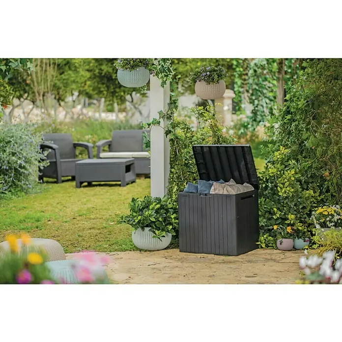 Keter Gartenbox City Box - L x B x H: 44 x 57,8 x 55 cm, Kunststoff, Anthrazit - Eine dunkelgraue Gartenbox steht auf einer Terrasse, umgeben von üppigem Grün, die zur Aufbewahrung von Gartenutensilien dient.