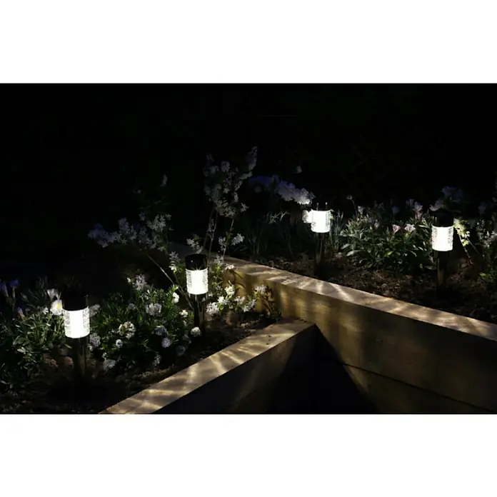 Luxform Estaca solar Rennes - Transparente, Negro, 5 lm - Varias luces solares iluminan un jardín de flores por la noche, que está rodeado de vigas de madera clara.